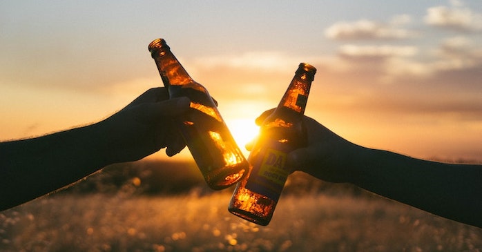 Two beer bottle clinking in the sunset