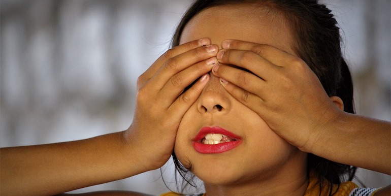 Child with her eyes covered by her hands